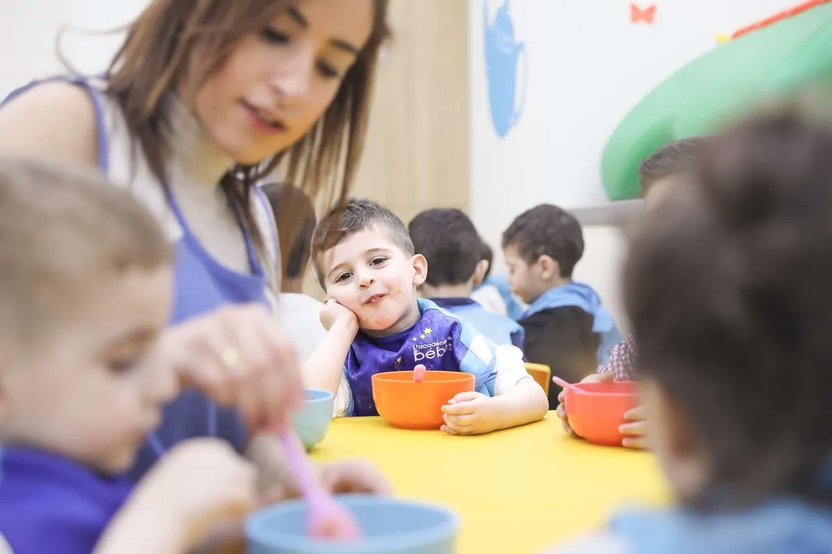 Preschoolers sharing a healthy meal with their teacher around a yellow table